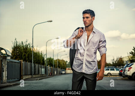 Handsome young man in elegant white shirt standing outdoor in street with large copyspace Stock Photo