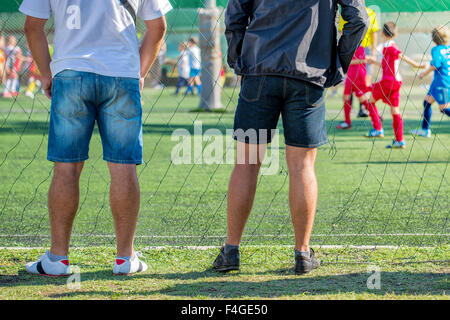 Fathers watching their sons playing soccer game, kids playing football, selective focus Stock Photo