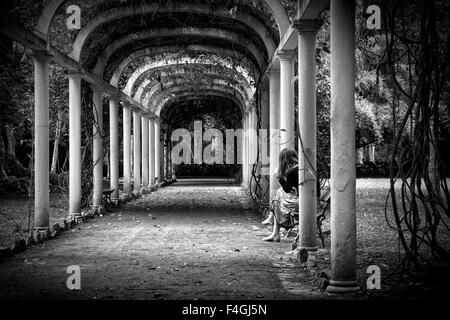 Black and white image of a young woman seated under an arbor at the Botanical Garden in Rio de Janeiro, Brazil. Stock Photo