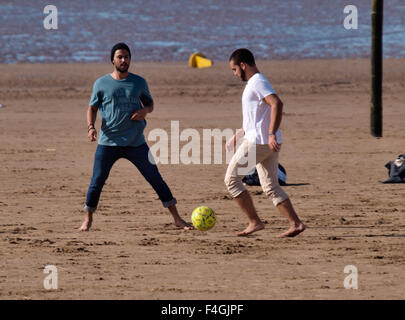 Multi-racial group of young men playing football on the beach, Weston-super-Mare, Somerset, UK Stock Photo