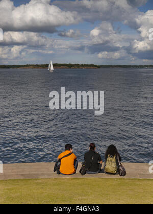 Three people looking out to sea on the Island Fortress of Suomenlinna, in Helsinki, Finland Stock Photo