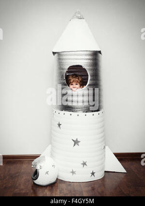 Happy child dressed in an astronaut costume playing with hand made rocket. Stock Photo