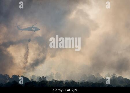 A Texas Army National Guard UH-60 Black Hawk helicopter drops water on the Hidden Pines Fire October 17, 2015 near Bastrop, Texas. Stock Photo