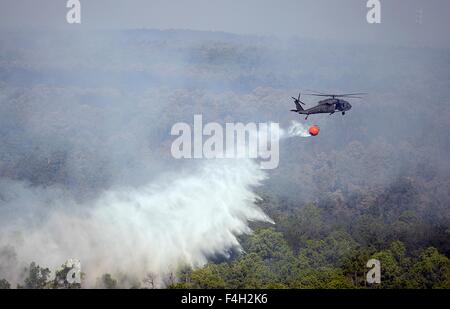 A Texas Army National Guard UH-60 Black Hawk helicopter drops water on the Hidden Pines Fire October 15, 2015 near Bastrop, Texas. Stock Photo