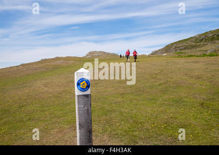 Wales coast path and footpath sign with walkers walking on south western tip of  Lleyn Peninsula / Pen Llyn, Gwynedd, Wales, UK Stock Photo