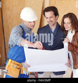 Construction: Young Couple Look At Home Plans with Builder Stock Photo