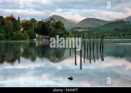 Remains of an old jetty with the fells and a boathouse at dawn reflected on Derwent Water in the Lake District National Park, Keswick, Cumbria Stock Photo