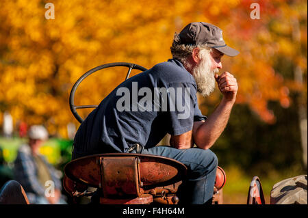 A farmer sits on his tractor on an autumn day in New Hampshire, USA. Stock Photo