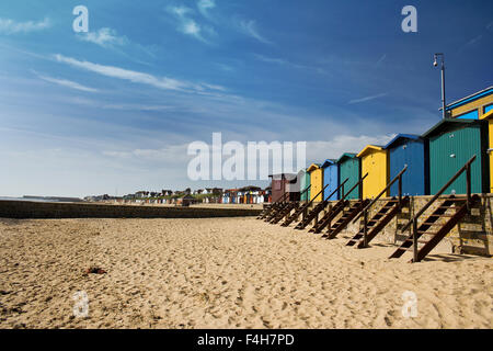 Colourful beach huts on sandy beach with blue sky at Walton On The Naze, Essex, England Stock Photo