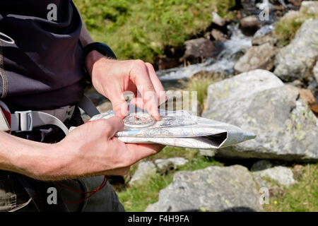 Hiker taking a bearing using a hiking map and compass for navigating a right direction in British mountains seen from side. Wales UK Britain Stock Photo