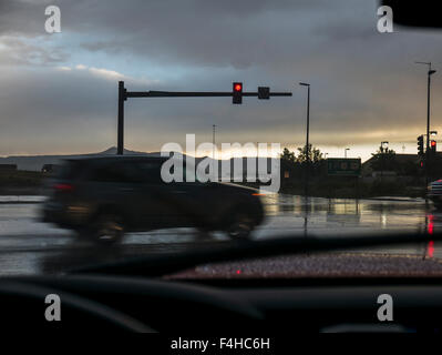 Windshield view of automobile moving through intersection; rain storm; traffic light;  Rock Springs: Wyoming; USA Stock Photo