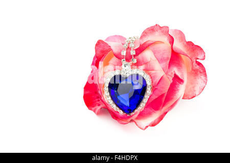 Blue jewelry heart hanging in red rose isolated on white background Stock Photo
