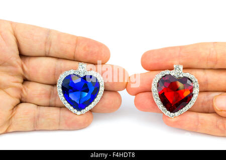 Two jewelry hearts on male and female hand isolated on white background Stock Photo