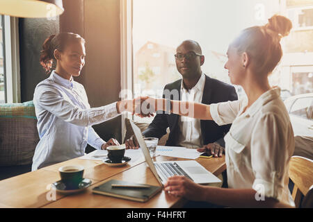 Black business woman and white business woman shaking hands closing a deal Stock Photo