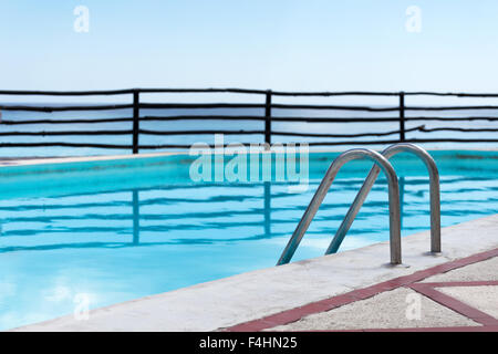 Grab bars ladder in swimming pool, outdoors at the day time Stock Photo