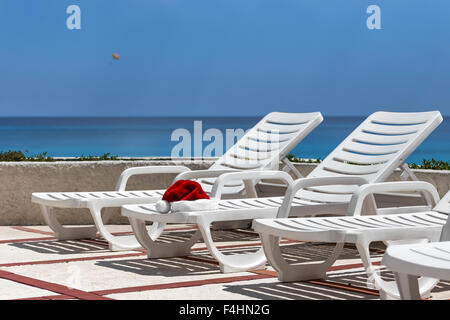 Santa Claus Hat on sunbed near swimming pool. Christmas vacation concept Stock Photo