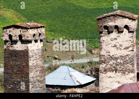 A backpacker seen between two Svan towers in Chazhashi, in Svaneti district, Caucasus mountains, northern Georgia. Stock Photo