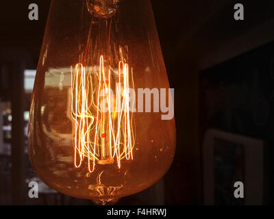 Old style dusty light bulb glowing in the dark Stock Photo