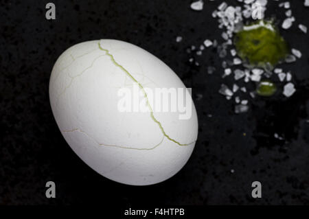 Egg with cracked shell on a black background Stock Photo