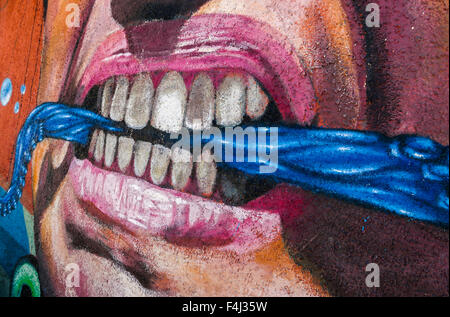 VALPARAISO, CHILE - OCTOBER 29, 2014: Colourful graffiti detail of an aggressive face with scarf between the teeth in Valparaiso Stock Photo