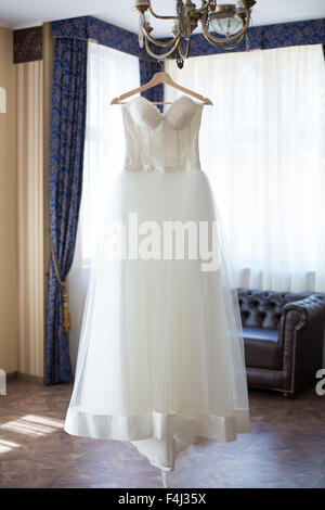 wedding dress hanging on the chandelier in the interior Stock Photo