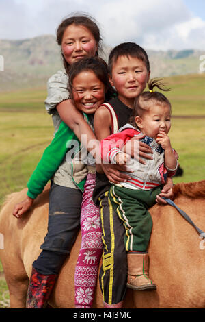 Portrait of four smiling and happy nomad siblings on their tame horse at summer nomad camp, Khujirt, Uvurkhangai, Mongolia Stock Photo