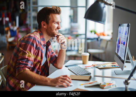 Happy man looking at computer screen with data while making final decision Stock Photo