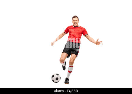 Full length portrait of a determined young football player shooting a ball and looking at the camera Stock Photo