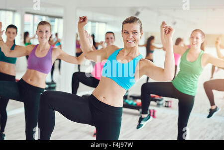 Group of enthusiastic young women in bright colored clothes practicing aerobics in a gym in a health and fitness concept Stock Photo
