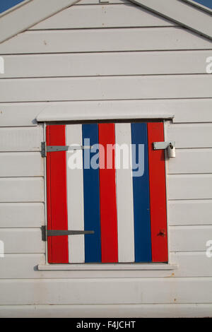 Painted red white and blue closed wooden shutter on a white painted beach hut at Southwold Suffolk England Stock Photo