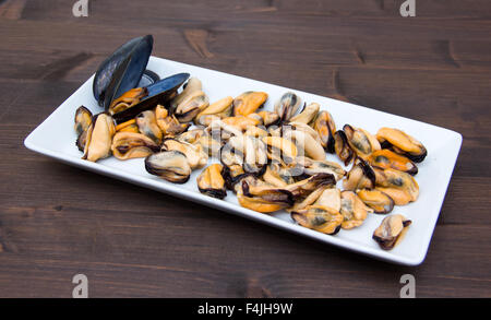 Mussels without shells on tray on wooden table Stock Photo