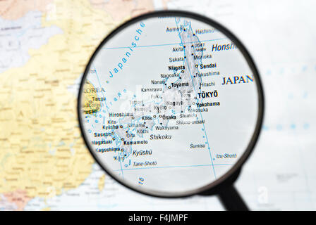 Magnifier focuses Japan on a map. Stock Photo