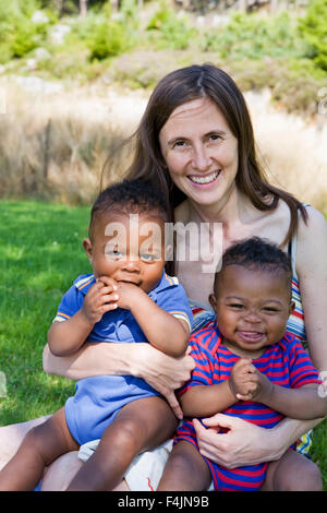 Sweden, Gothenburg, portrait of mother embracing sons (12-17 months) outdoors Stock Photo