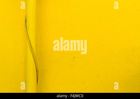 Yellow pipe in front of yellow residential building wall Stock Photo
