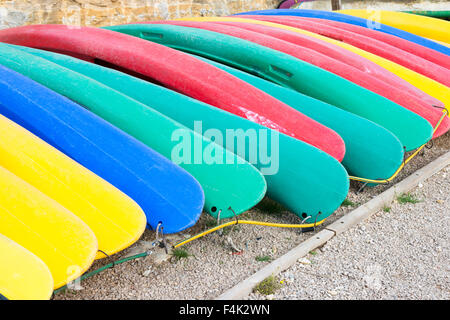 Colourful Canoes or Kayaks lined up on the edge of a lake at Esparron de Provence ready to used for boat trips Stock Photo