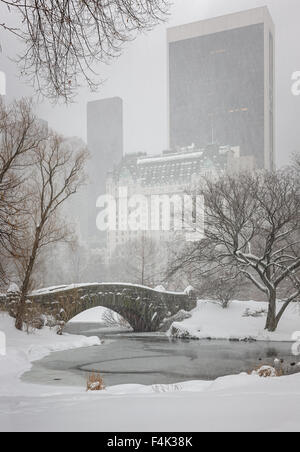 Snowfall on Central Park's Gapstow Bridge and the Pond . Quiet winter scene, with a view on Manhattan's Skyscrapers, New York Stock Photo