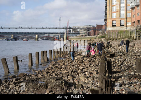 Low tide at the Thames Bank below the Millenium Bridge showing modern mudlarks hunting for hidden treasure exposed by the tide Stock Photo