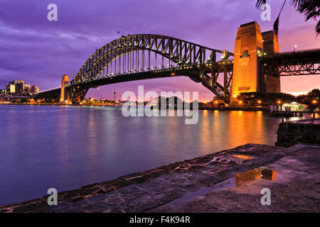 Sydney harbour bridge side view from Milsons point after fresh rain when brightly illuminated bridge arch and column reflecting Stock Photo