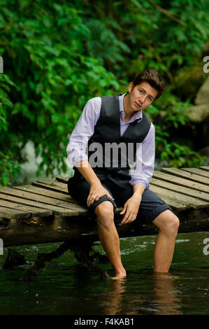 Elegant young man enjoying the nature with his feet inside a lake Stock Photo