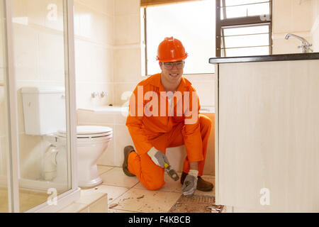 handsome young contractor removing old floor tiles in bathroom Stock Photo