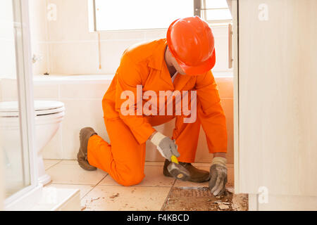 construction worker removing old floor tiles using a hammer and chisel Stock Photo