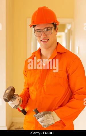 portrait of young builder holding chisel and hammer Stock Photo