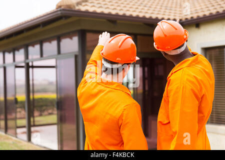 rear view of contractors pointing at house under construction Stock Photo