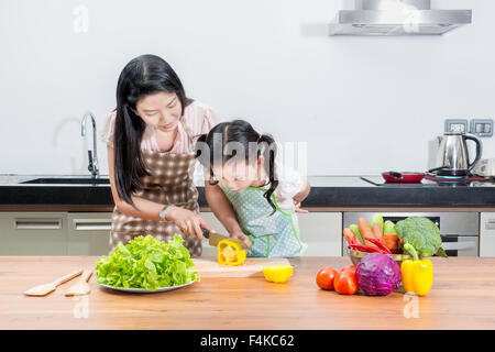 family, children and happy people concept - Asian mother and kid daughter cooking in the kitchen at home Stock Photo