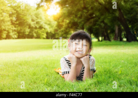 Little asian girl laying down on the green grass Stock Photo