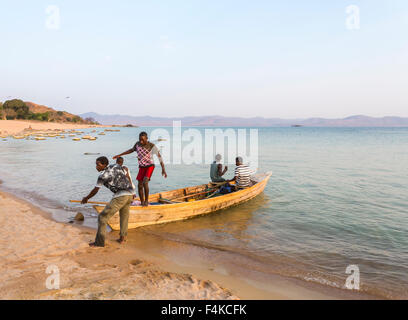 Landscape view of local lifestyle: fishermen in a wooden boat returning after fishing, Kaya Mawa, Likoma Island, Lake Malawi, Malawi, southeast Africa Stock Photo