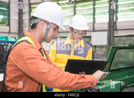 Asian Mechanical Engineer using computer-aided to do planning and control equipment in factory Stock Photo