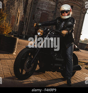 Man sitting on a cafe-racer motorcycle outdoors