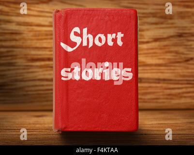 Old red short stories book on wooden background closeup Stock Photo