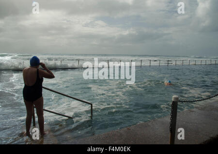 Older woman preparing to swim in rough sea conditions at Newport Beach ocean pool in Sydney, Australia Stock Photo